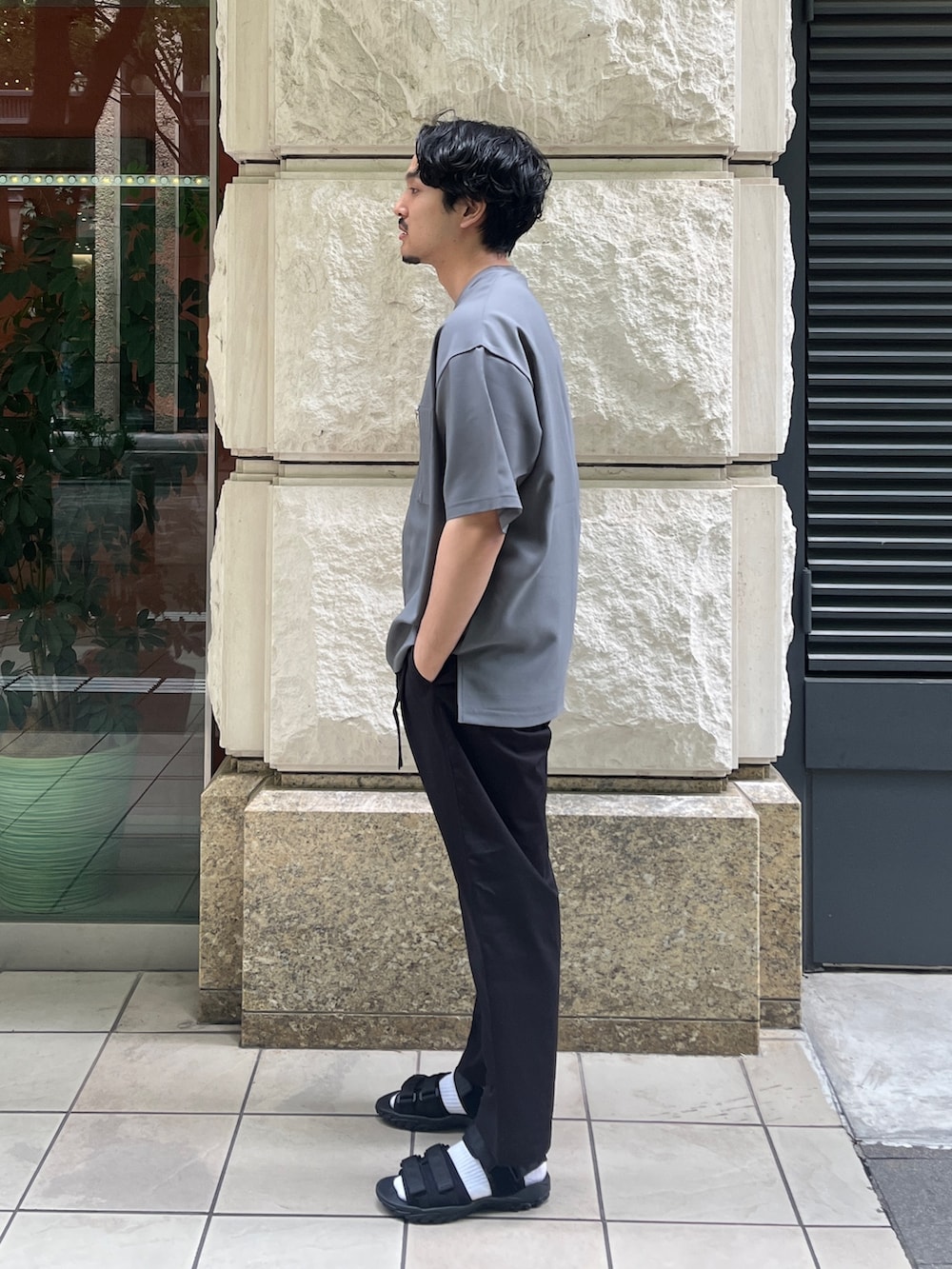 グレー系のTシャツ/カットソー、ブラック系のスラックスを着用したメンズの夏コーディネートの2枚目の写真