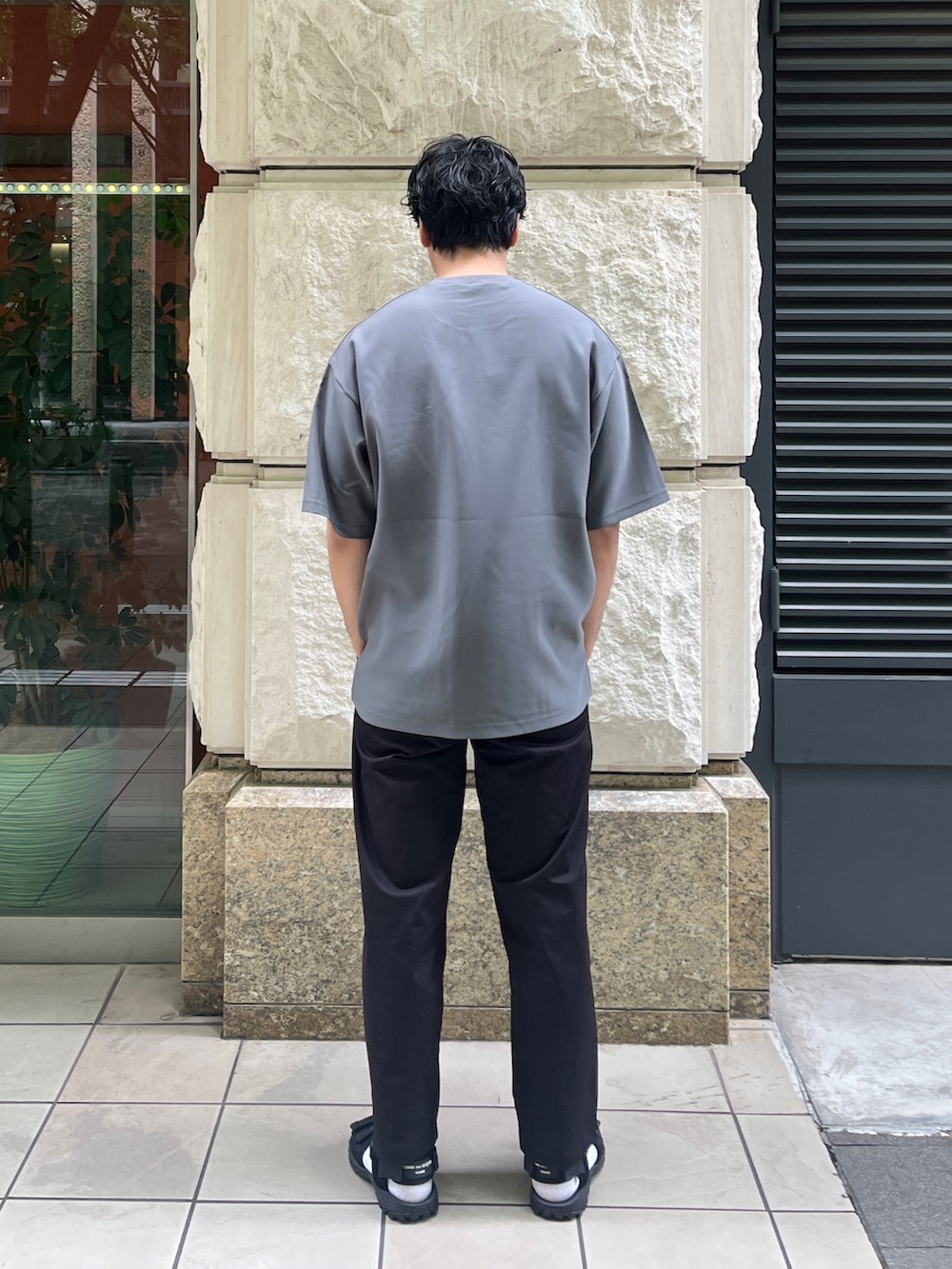 グレー系のTシャツ/カットソー、ブラック系のスラックスを着用したメンズの夏コーディネートの3枚目の写真