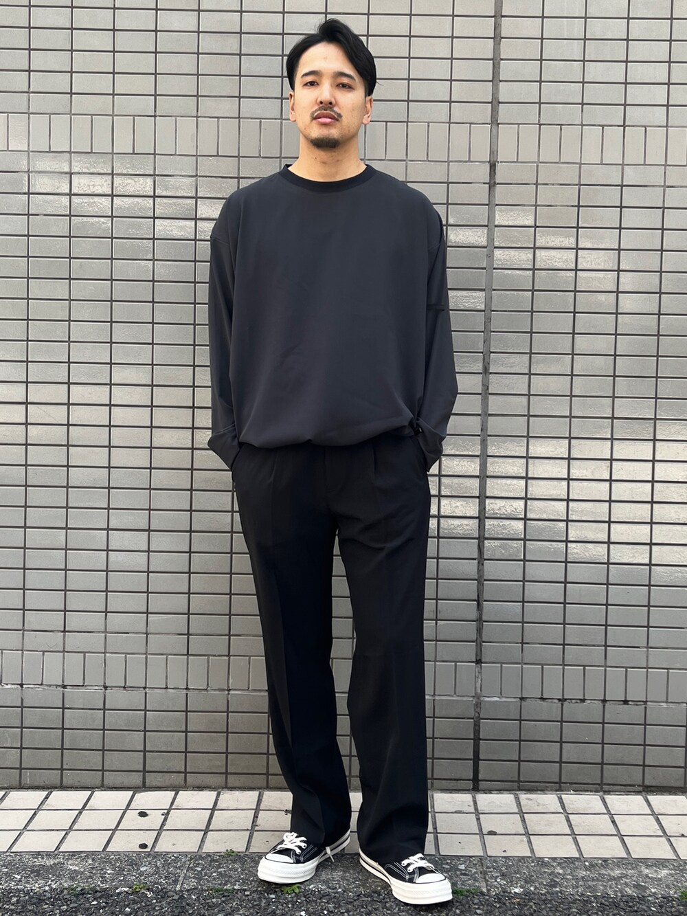 グレー系のTシャツ/カットソー、ブラック系のスラックスを着用したメンズの春コーディネートの2枚目の写真