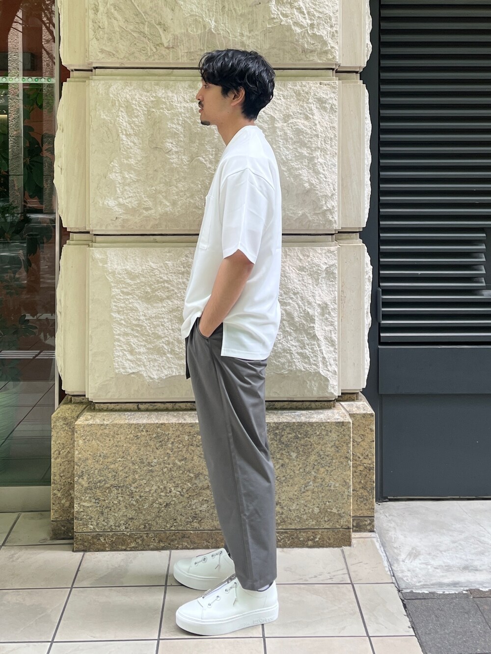 ホワイト系のTシャツ/カットソー、グリーン系のスラックスを着用したメンズの夏コーディネートの2枚目の写真