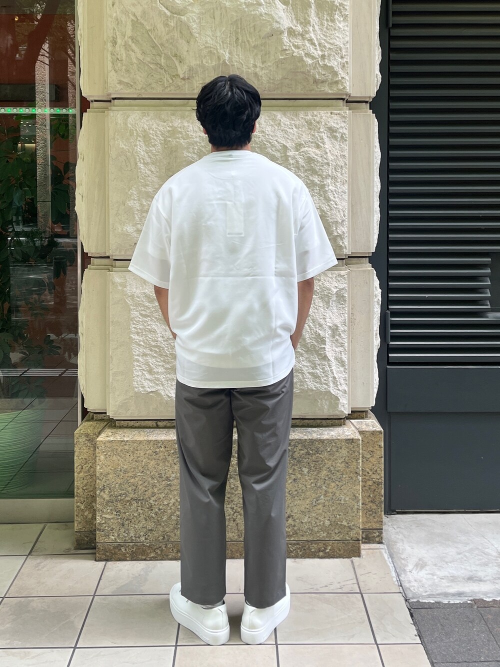 ホワイト系のTシャツ/カットソー、グリーン系のスラックスを着用したメンズの夏コーディネートの3枚目の写真