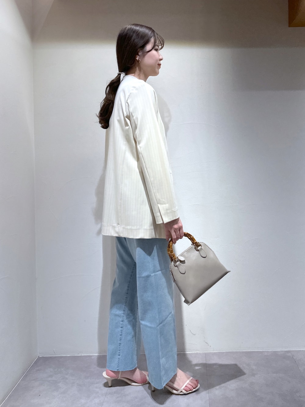 ホワイト系のサンダル、グレー系のショルダーバッグ、ブルー系のデニムパンツを着用したレディースの春コーディネートの5枚目の写真