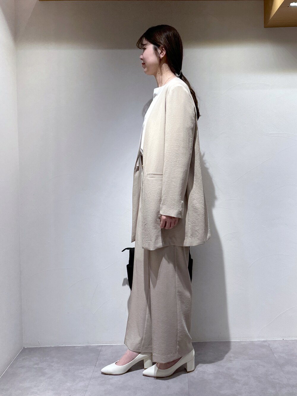 ブラック系のトートバッグ、ホワイト系のパンプス、ベージュ系のスラックスを着用したレディースの春コーディネートの3枚目の写真