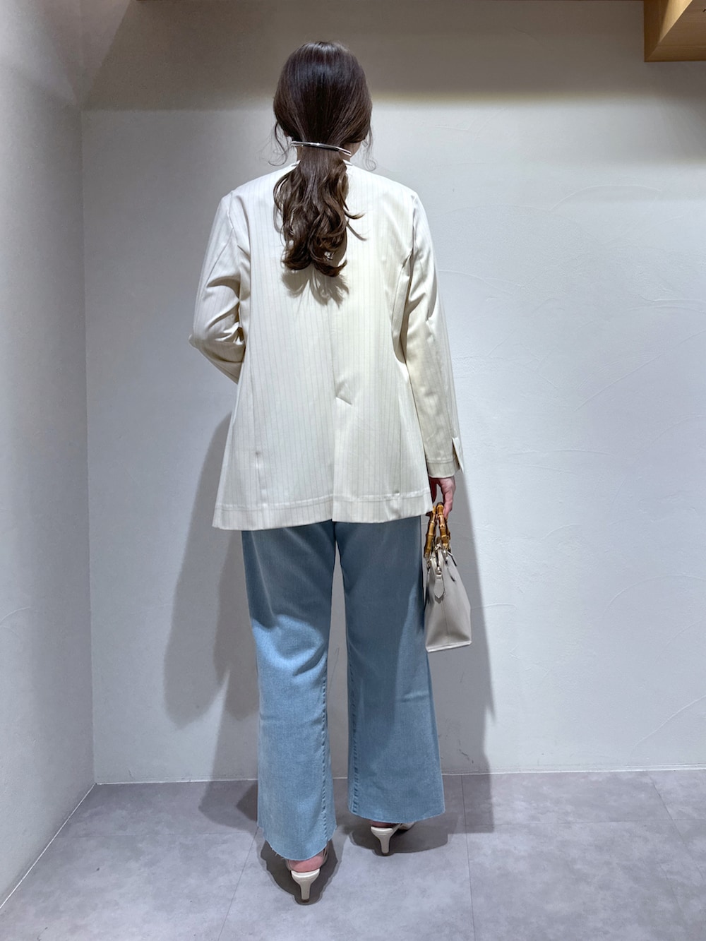 ホワイト系のサンダル、グレー系のショルダーバッグ、ブルー系のデニムパンツを着用したレディースの春コーディネートの4枚目の写真