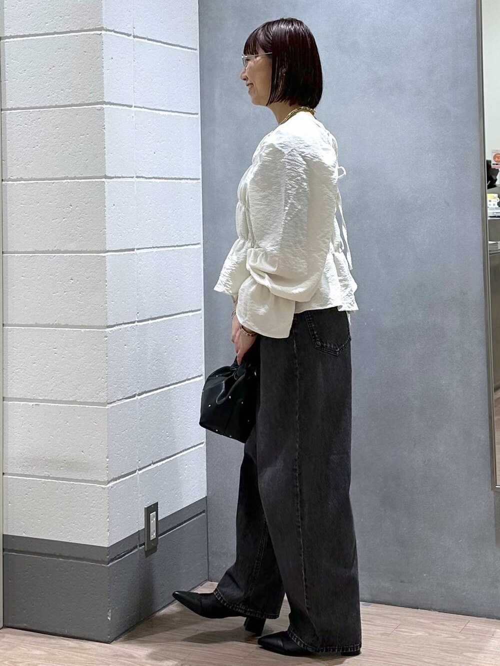 ブラック系のハンドバッグ、グリーン系のタンクトップ、ホワイト系のシャツ/ブラウスを着用したレディースの春コーディネートの4枚目の写真