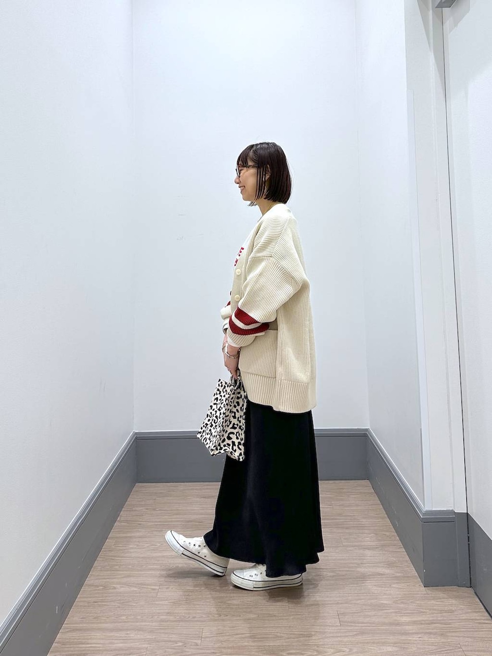 ホワイト系のニット/セーター、ホワイト系のTシャツ/カットソー、ブラック系のスカートを着用したレディースの冬コーディネートの4枚目の写真