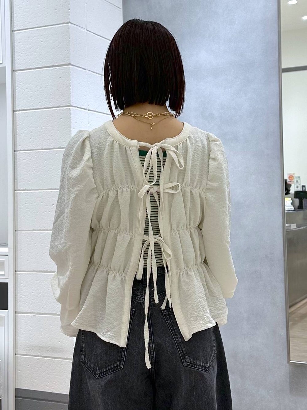 ブラック系のハンドバッグ、グリーン系のタンクトップ、ホワイト系のシャツ/ブラウスを着用したレディースの春コーディネートの7枚目の写真