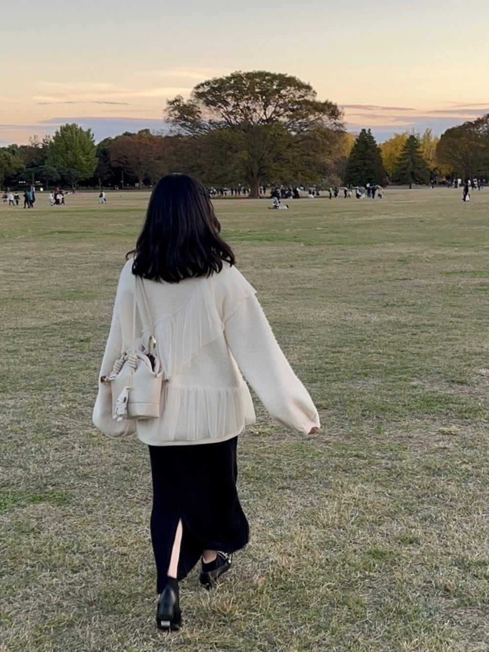 ホワイト系のニット/セーター、ホワイト系のハンドバッグ、ブラック系のスカートを着用したレディースの冬コーディネートの2枚目の写真