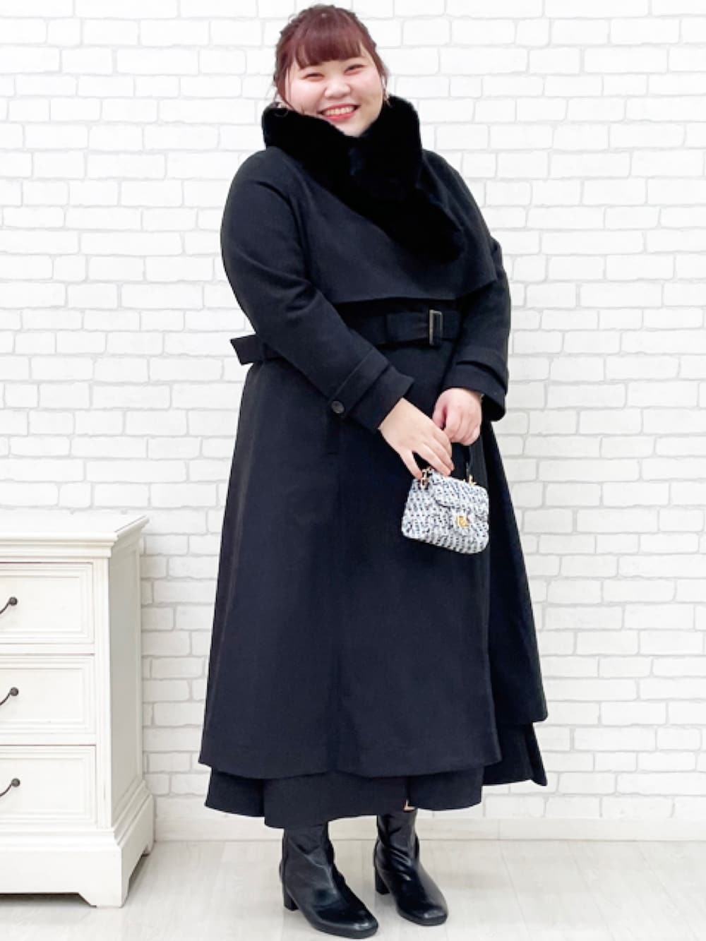 ブラック系のチェスターコート、ブラック系のスカートを着用したレディースの秋コーディネートの3枚目の写真