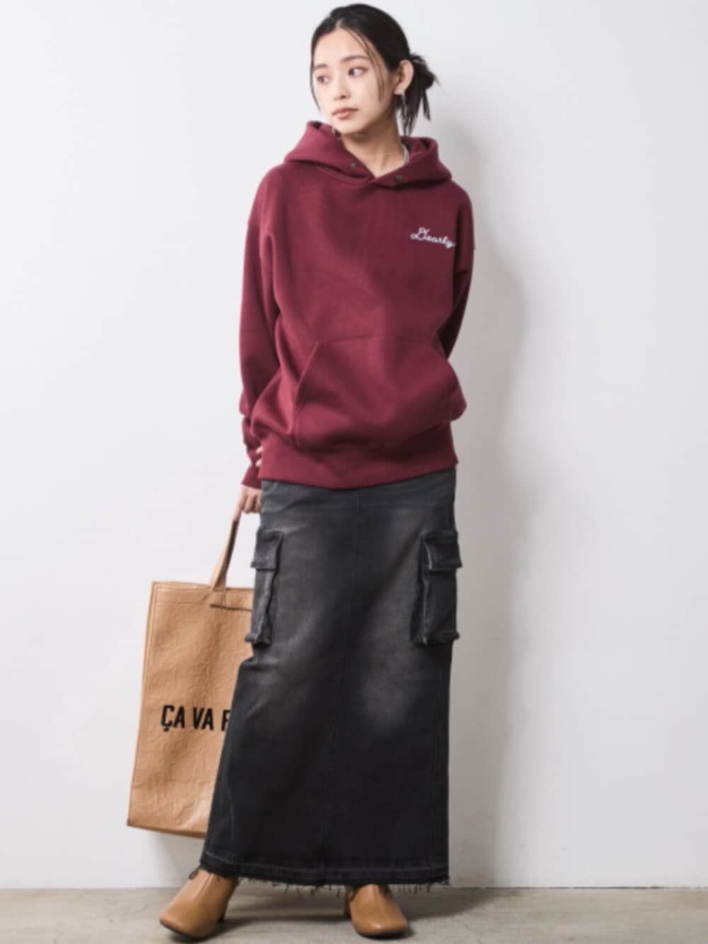 ブラック系のデニムスカート、ブラック系のブルゾン、レッド系のパーカーを着用したレディースの秋コーディネートの2枚目の写真