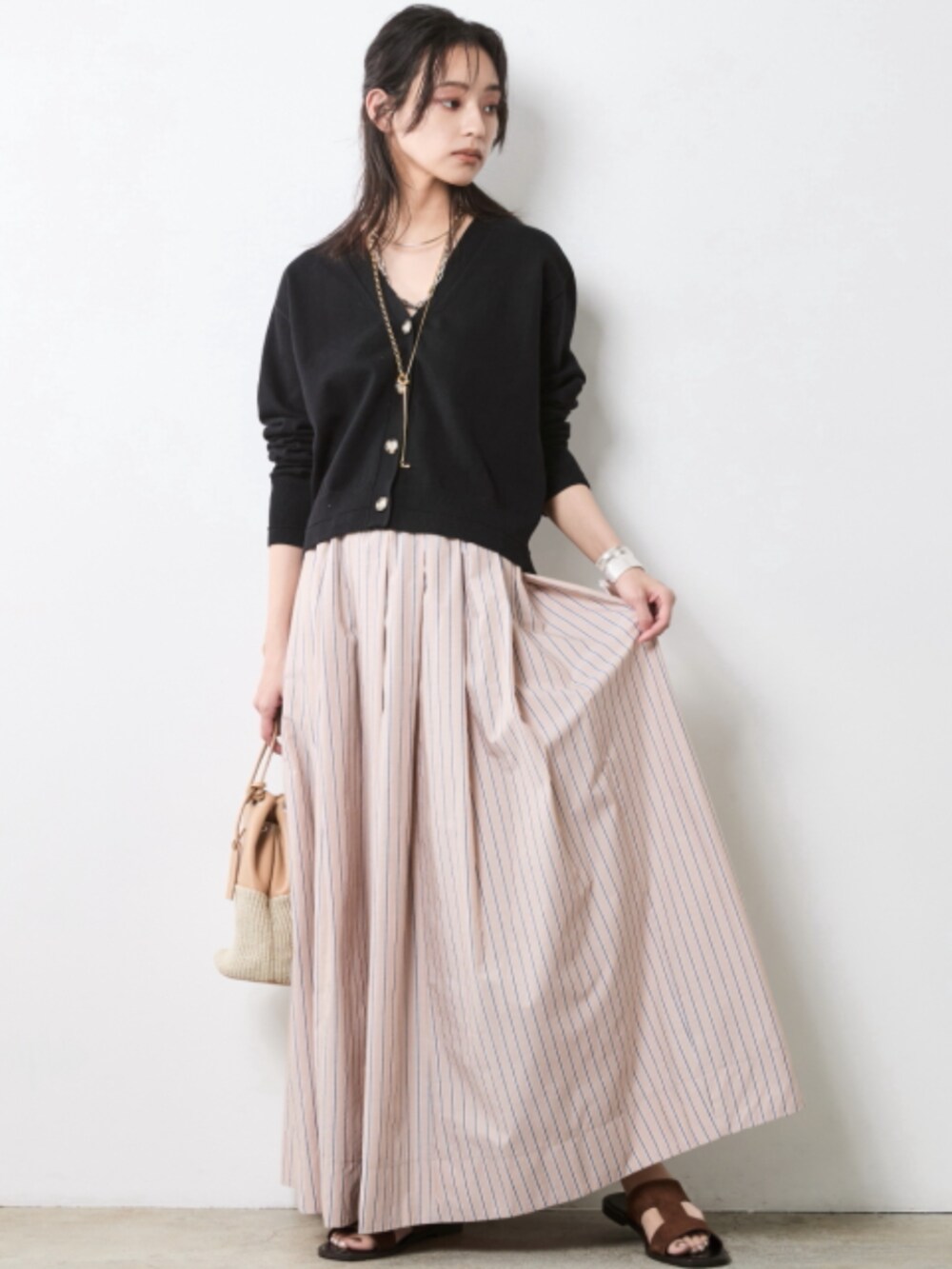 ベージュ系のスカート、ブラック系のカーディガン/ボレロを着用したレディースの春コーディネートの2枚目の写真