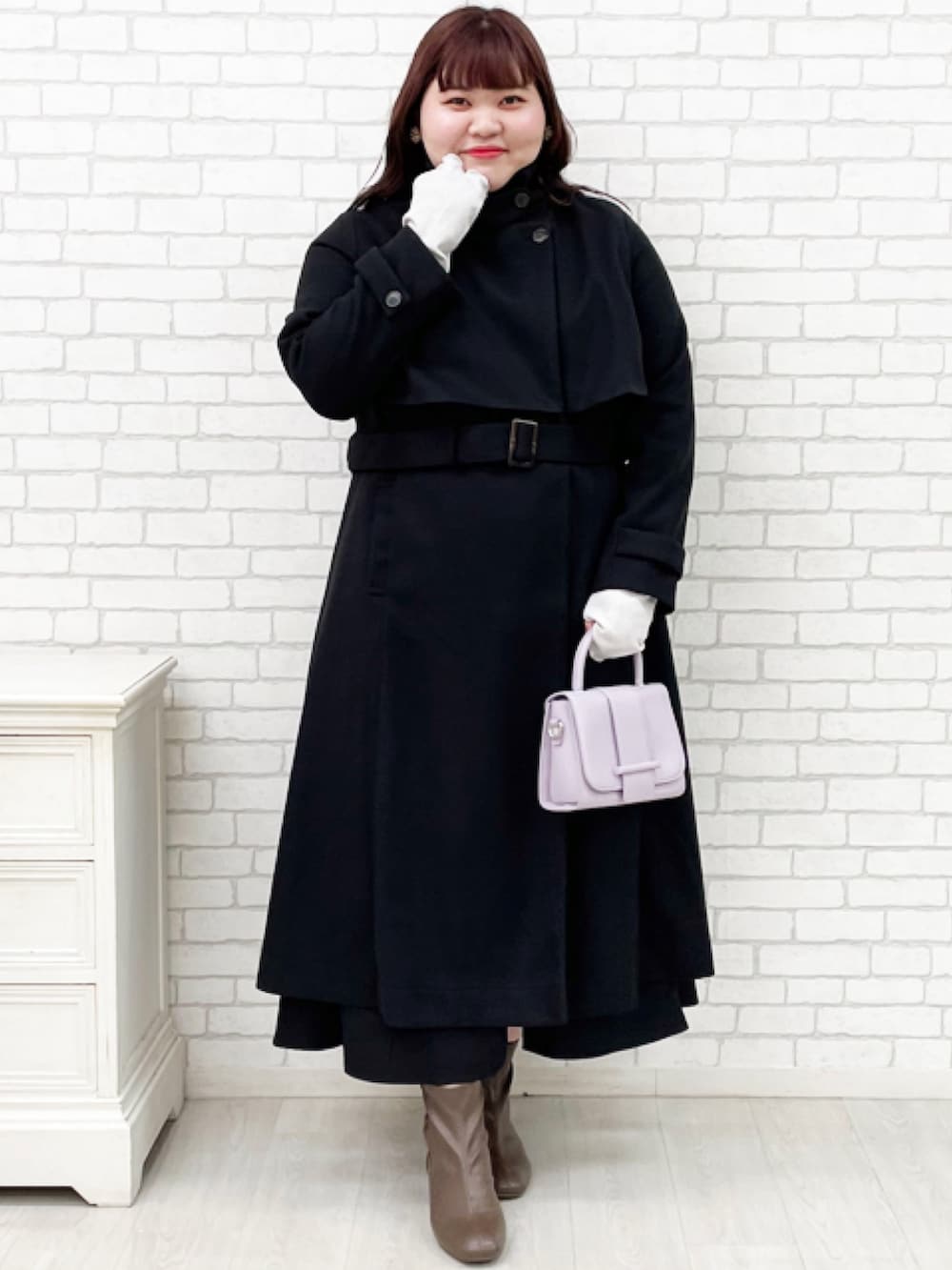 ブラック系のチェスターコート、ブラック系のスカートを着用したレディースの秋コーディネートの2枚目の写真