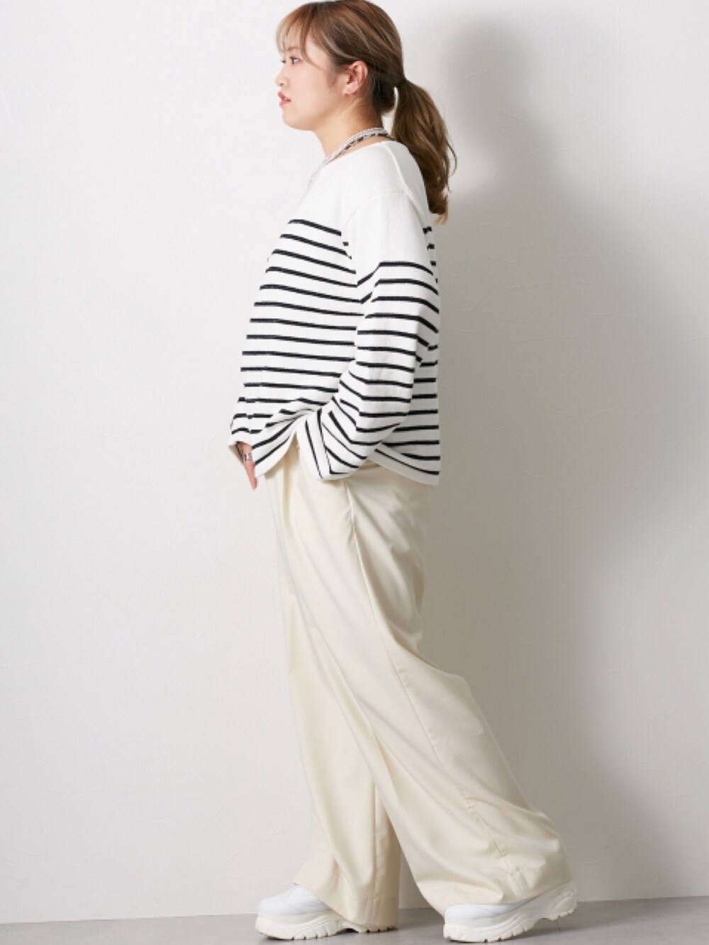 ホワイト系のニット/セーター、グレー系のパンツを着用したレディースの冬コーディネートの3枚目の写真