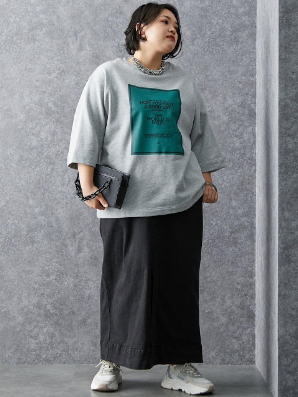 グレー系のスウェット、ブラック系のデニムスカートを着用したレディースの冬コーディネートの2枚目の写真