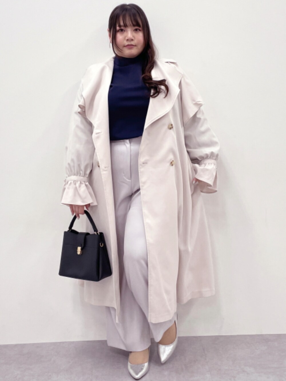 ブルー系のTシャツ/カットソー、ベージュ系のスラックス、ホワイト系のトレンチコートを着用したレディースの冬コーディネートの2枚目の写真
