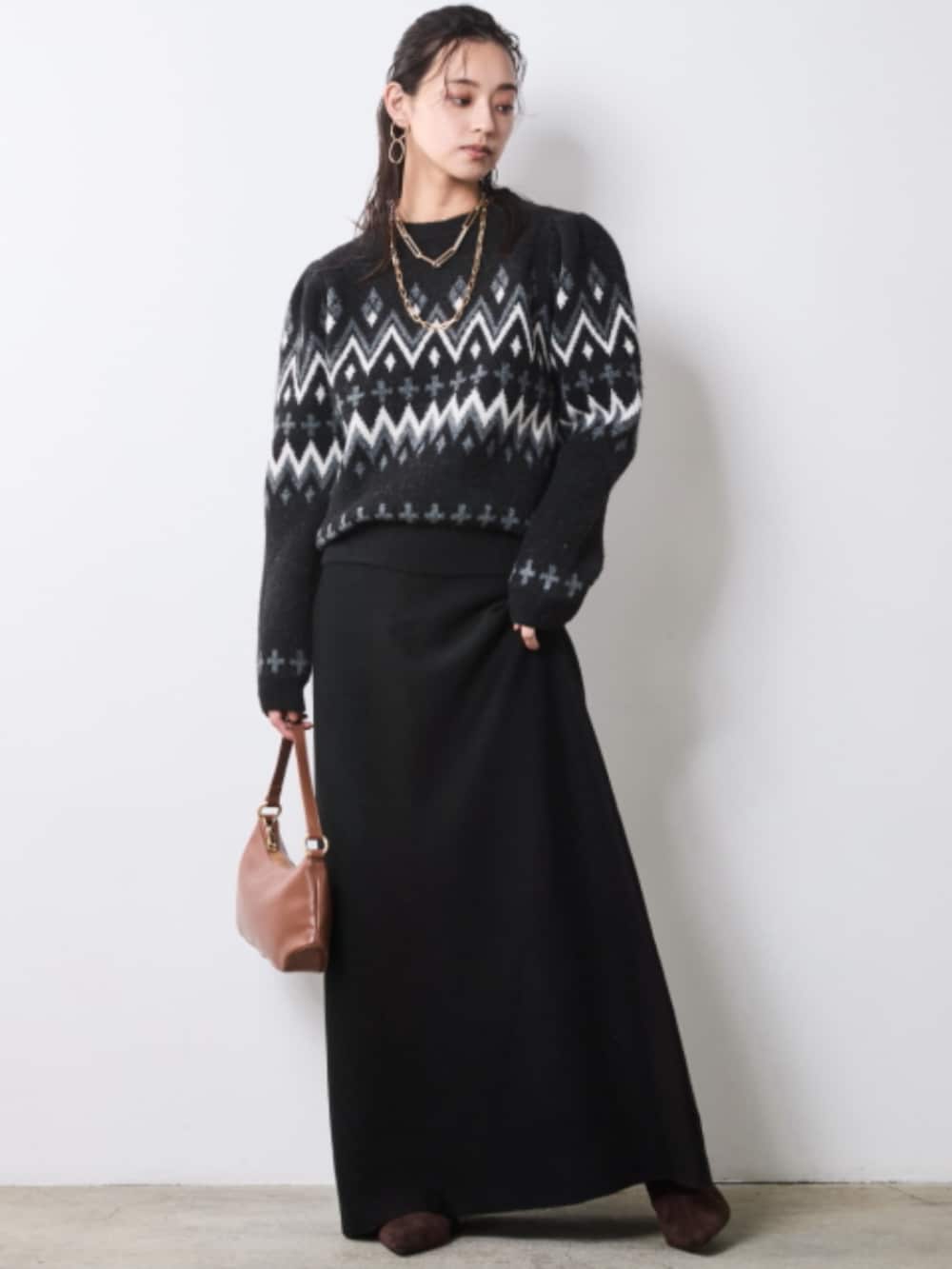 イエロー系のステンカラーコート、ブラック系のニット/セーター、ブラック系のスカートを着用したレディースの秋コーディネートの2枚目の写真