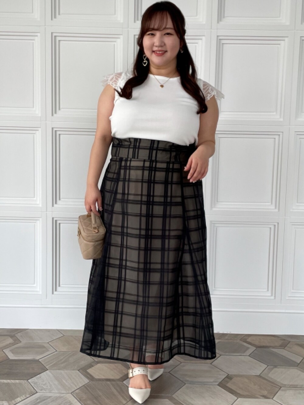 ブラック系のスカート、ホワイト系のニット/セーター、ブラック系のカーディガン/ボレロを着用したレディースの春コーディネートの2枚目の写真