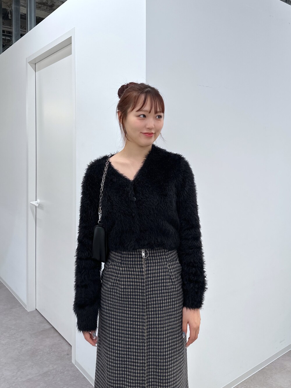 ブラック系のカーディガン/ボレロ、ベージュ系のスカート、ブラック系のハンドバッグを着用したレディースの冬コーディネートの4枚目の写真