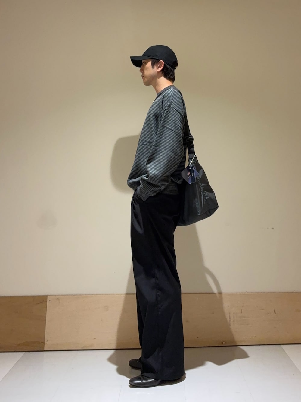 グレー系のニット/セーター、グレー系のショルダーバッグ、ブラック系のキャップを着用したメンズの秋コーディネートの2枚目の写真