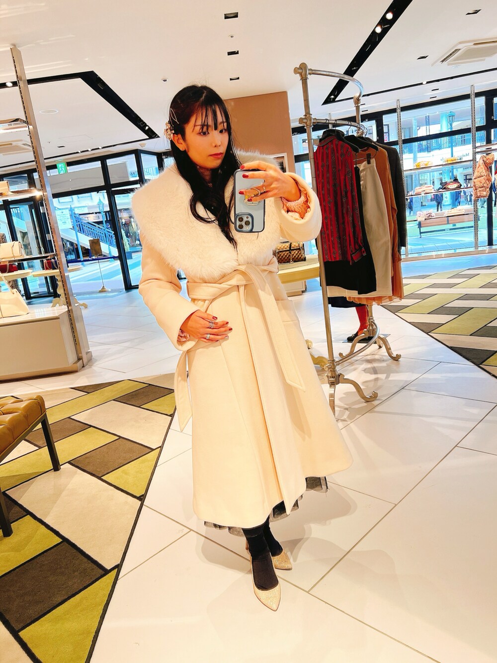 ベージュ系のトートバッグ、ピンク系のニット/セーター、シルバー系のクラッチバッグを着用したレディースの冬コーディネートの5枚目の写真