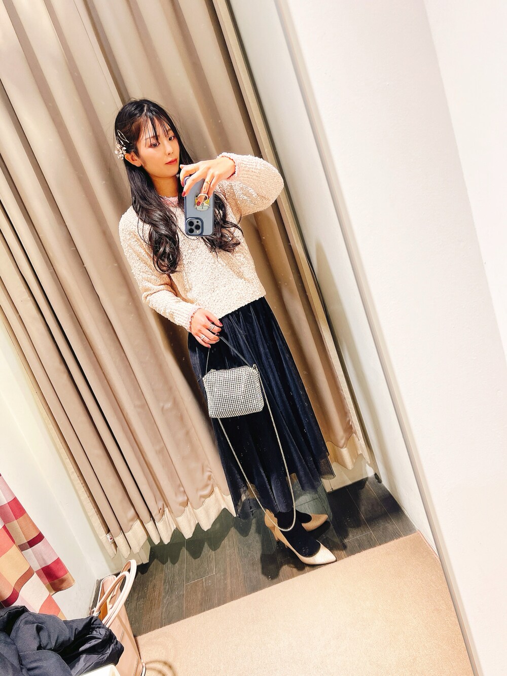 ベージュ系のトートバッグ、ピンク系のニット/セーター、シルバー系のクラッチバッグを着用したレディースの冬コーディネートの2枚目の写真