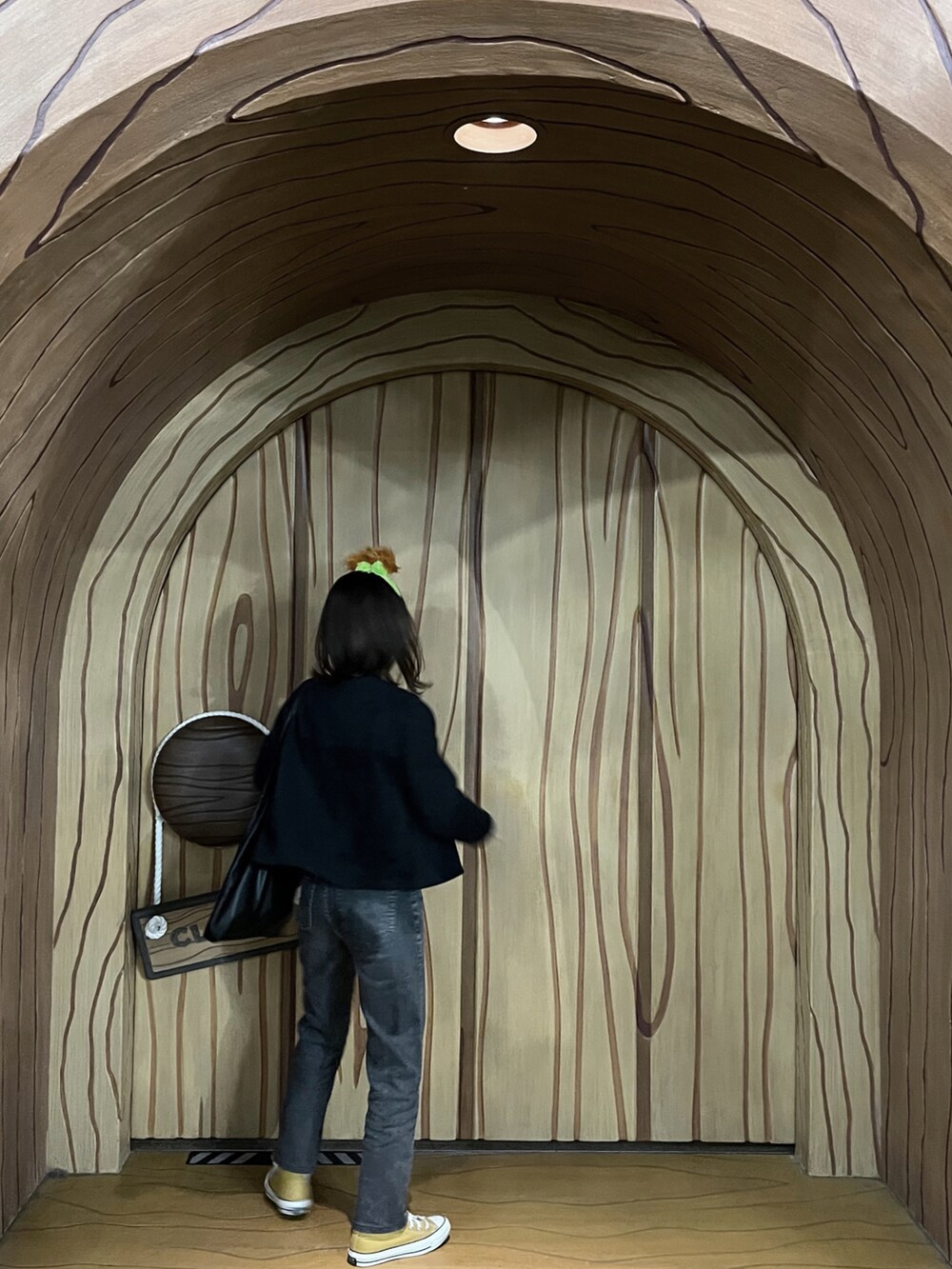 グリーン系のニット/セーター、グレー系のデニムパンツ、ブラック系のカーディガン/ボレロを着用したレディースの冬コーディネートの2枚目の写真