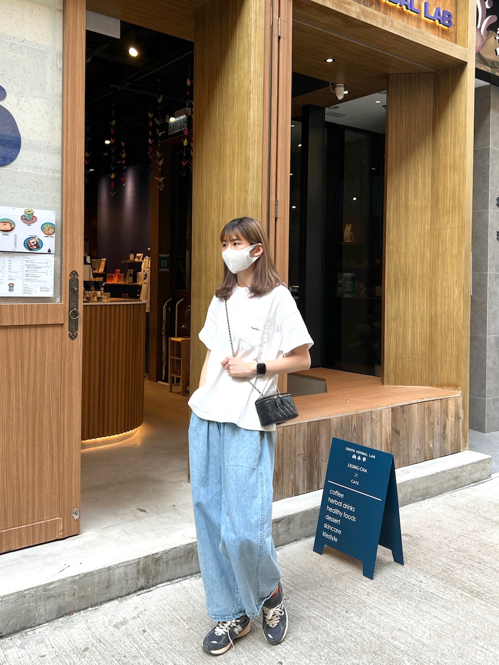 ホワイト系のTシャツ/カットソー、ブルー系のスニーカー、ブラック系のハンドバッグを着用したレディースの秋コーディネートの2枚目の写真