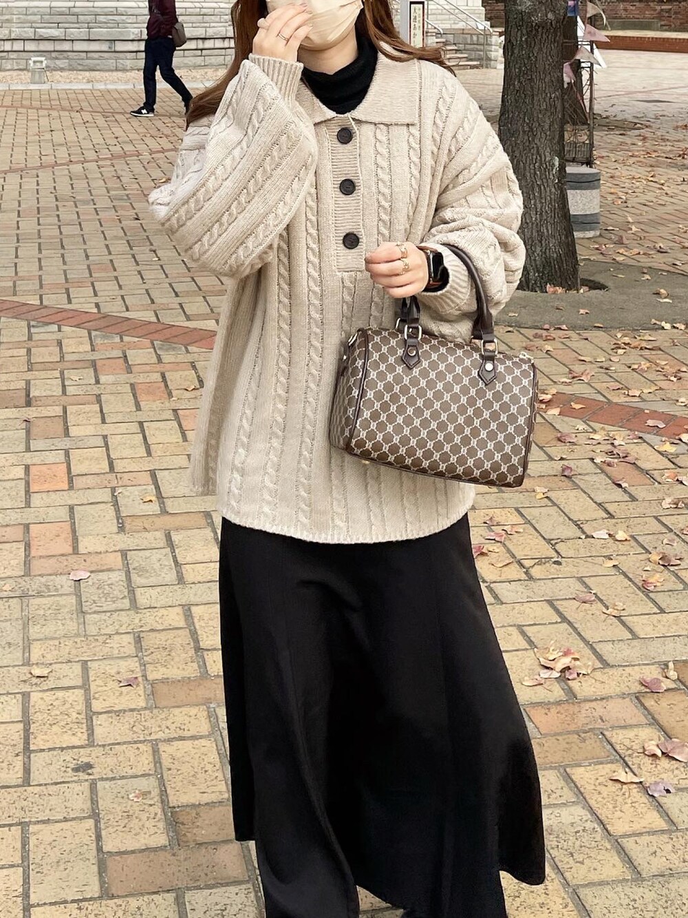 ブラック系のブーツ、ブラック系のスカート、ベージュ系のニット/セーターを着用したレディースの冬コーディネートの2枚目の写真