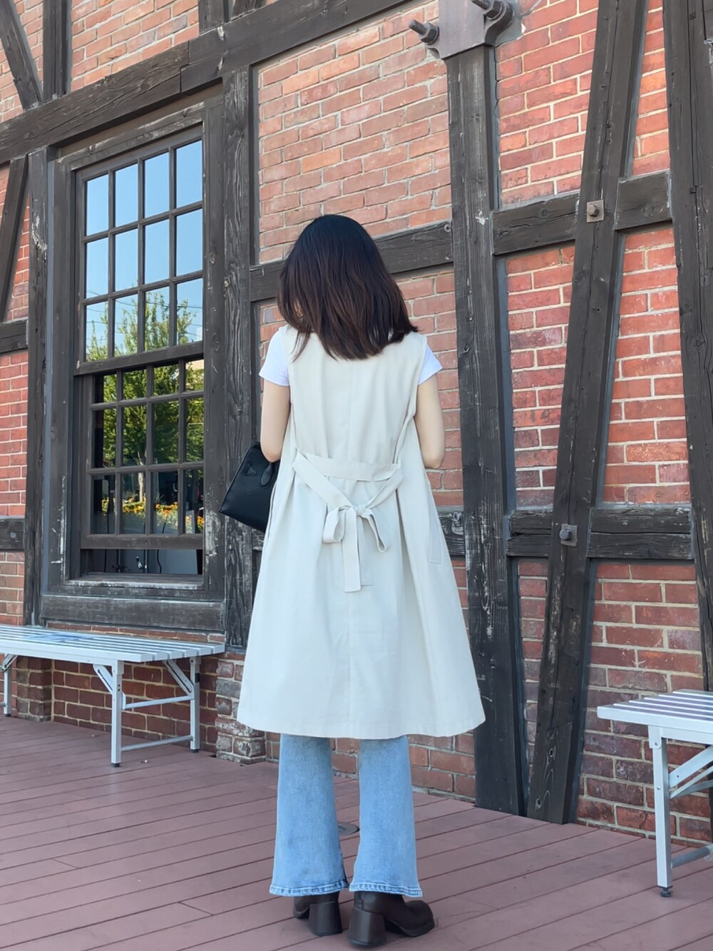 ブラック系のバッグ、ホワイト系のトップス、ベージュ系のジャケット/アウターを着用したレディースの夏コーディネートの2枚目の写真