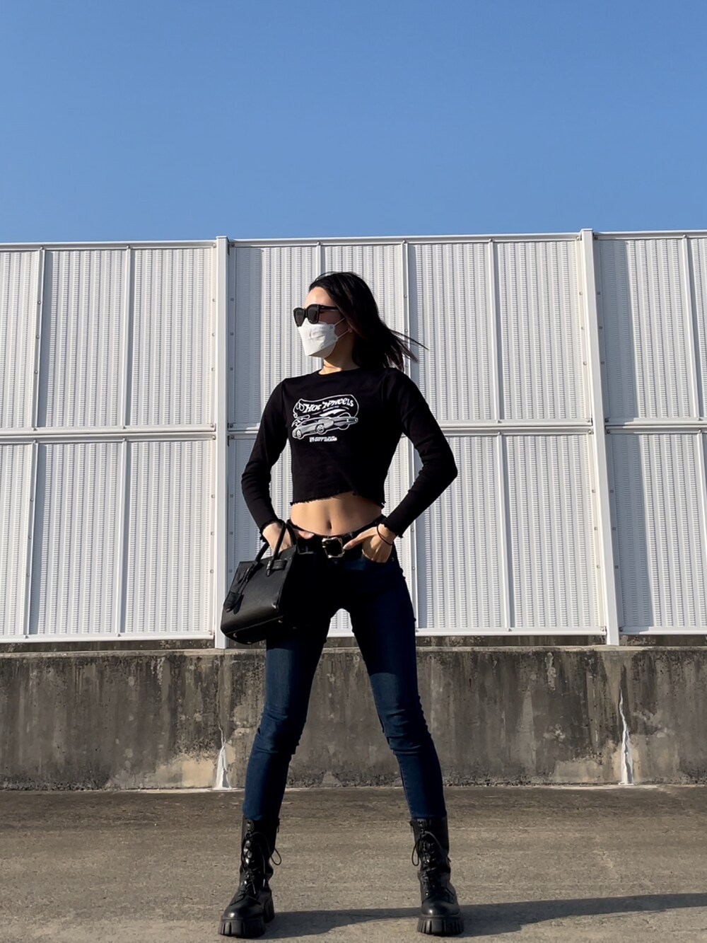 ブルー系のデニムパンツ、ブラック系のトップス、ブラック系のバッグを着用したレディースの春コーディネートの2枚目の写真