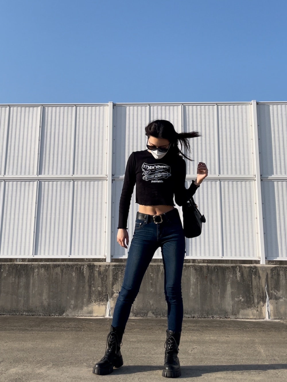 ブルー系のデニムパンツ、ブラック系のトップス、ブラック系のバッグを着用したレディースの春コーディネートの3枚目の写真