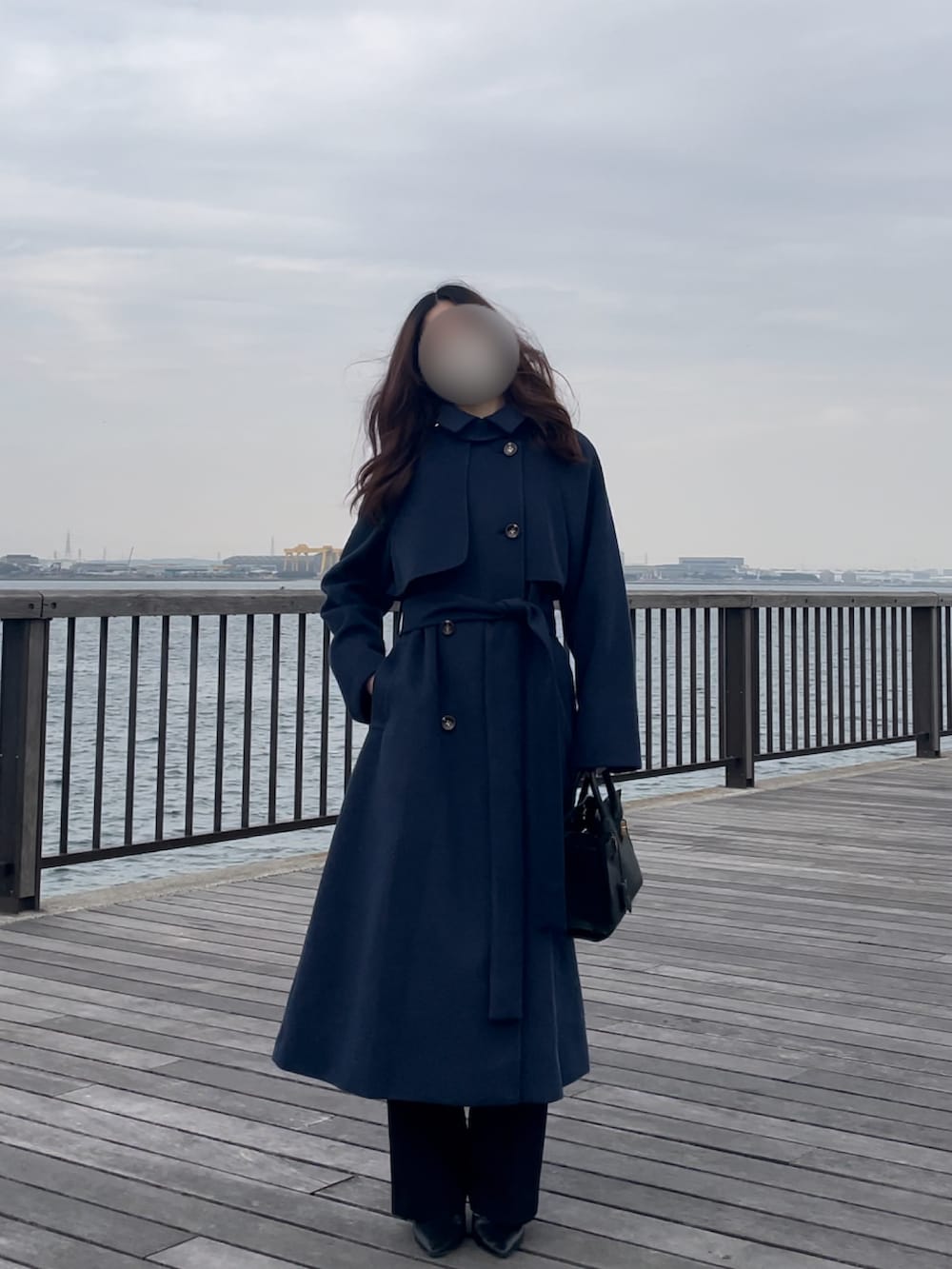 ブルー系のステンカラーコート、ブラック系のシューズ、ブラック系のバッグを着用したレディースの冬コーディネートの3枚目の写真