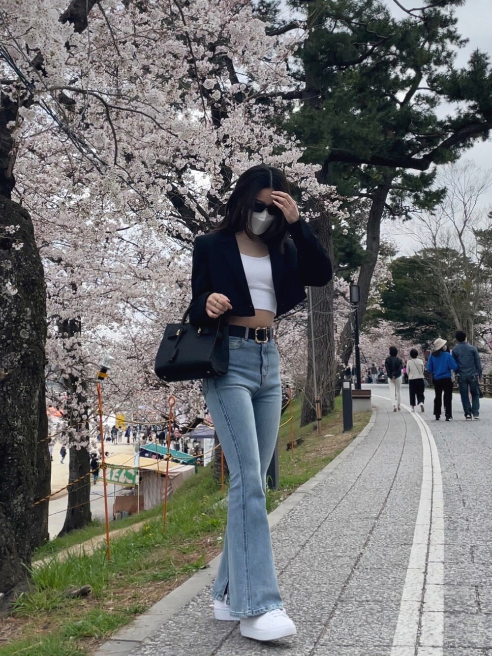 ブラック系のジャケット/アウター、ブルー系のデニムパンツ、ホワイト系のスニーカーを着用したレディースの春コーディネートの2枚目の写真