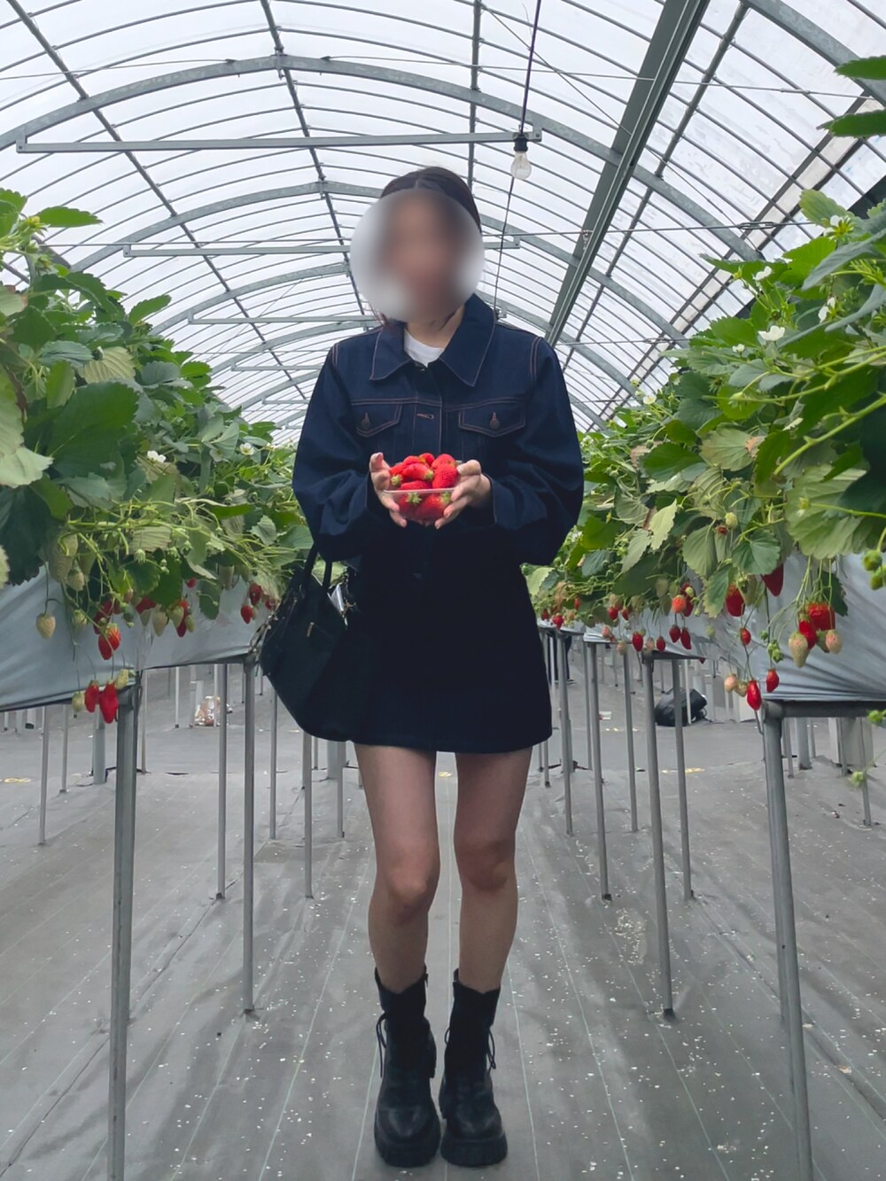 ブルー系のデニムジャケット、ブルー系のデニムスカート、ブラック系のバッグを着用したレディースの春コーディネートの2枚目の写真