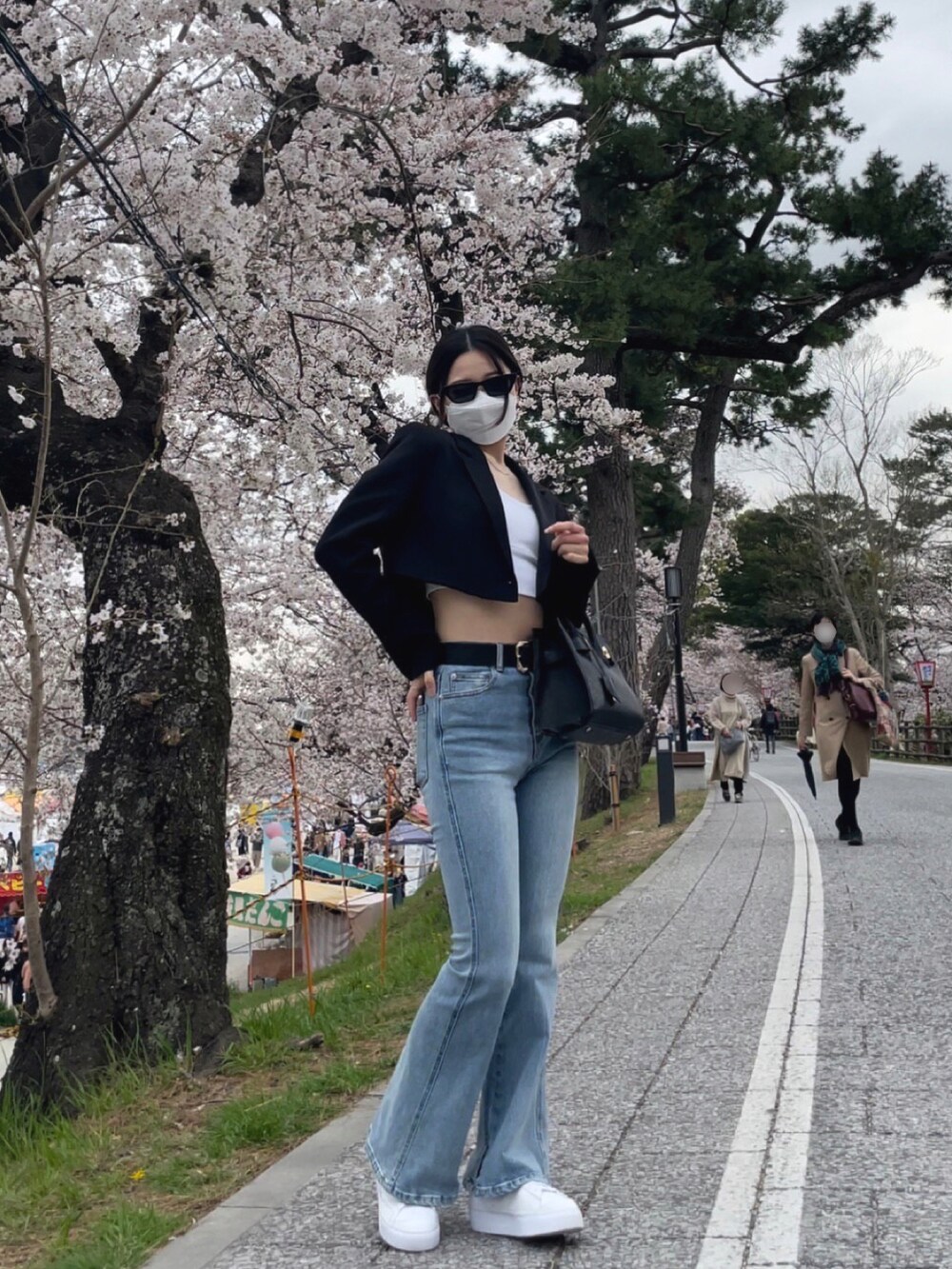 ブラック系のジャケット/アウター、ブルー系のデニムパンツ、ホワイト系のスニーカーを着用したレディースの春コーディネートの3枚目の写真