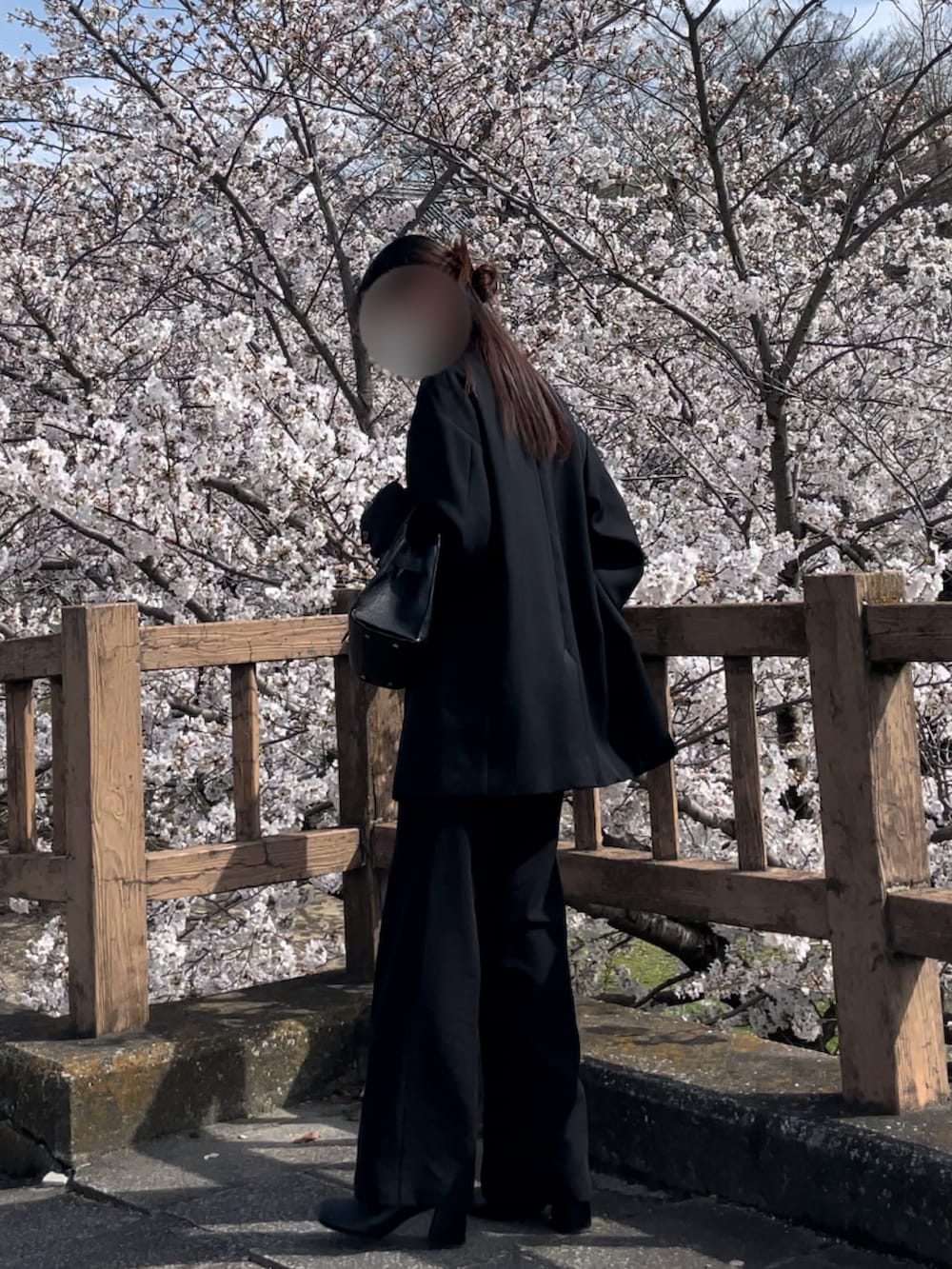 ブラウン系のトップス、ブラック系のジャケット/アウター、ブラック系のバッグを着用したレディースの春コーディネートの2枚目の写真