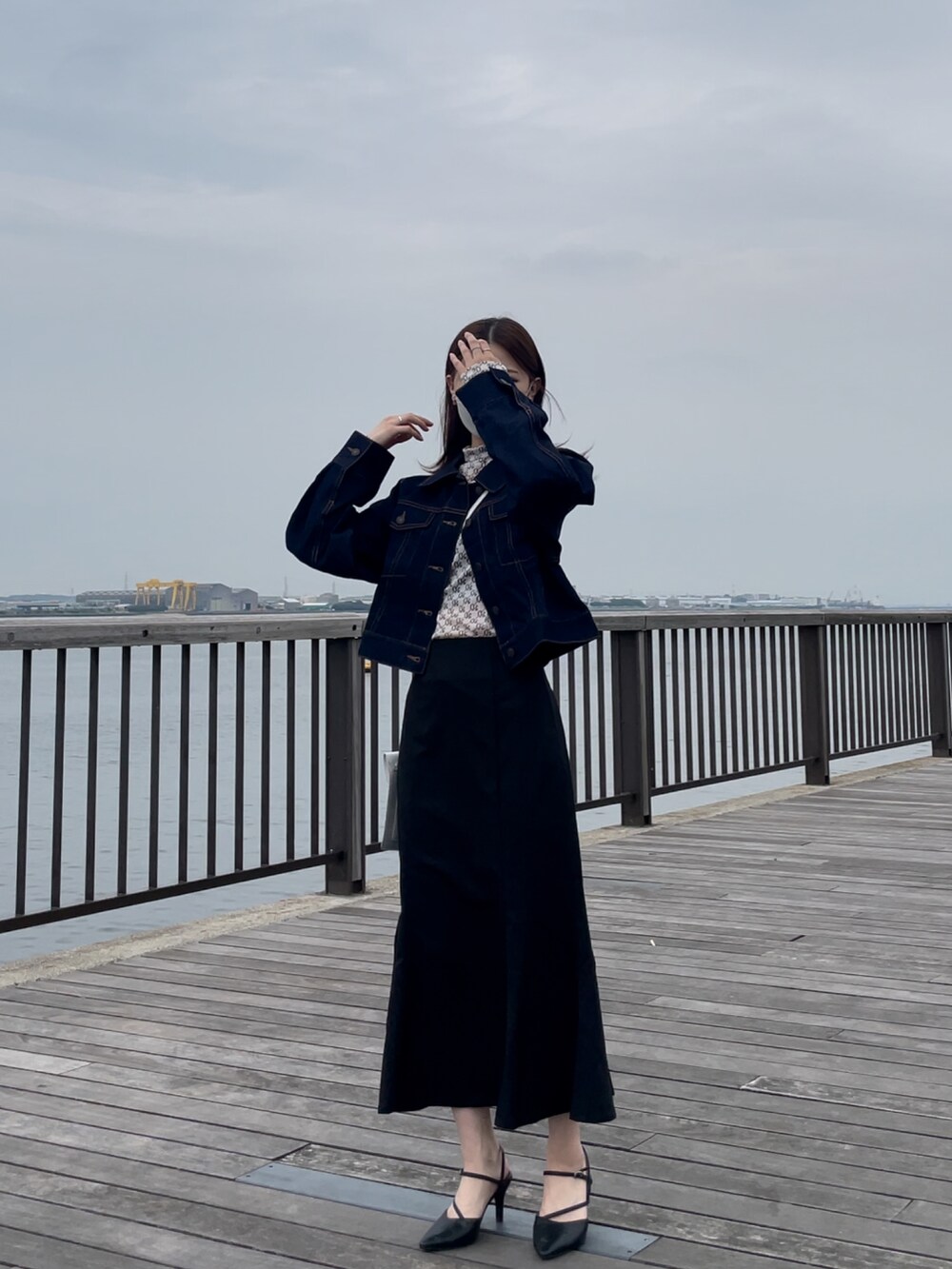 ブルー系のデニムジャケット、ホワイト系のトップス、ブラック系のスカートを着用したレディースの秋コーディネートの2枚目の写真