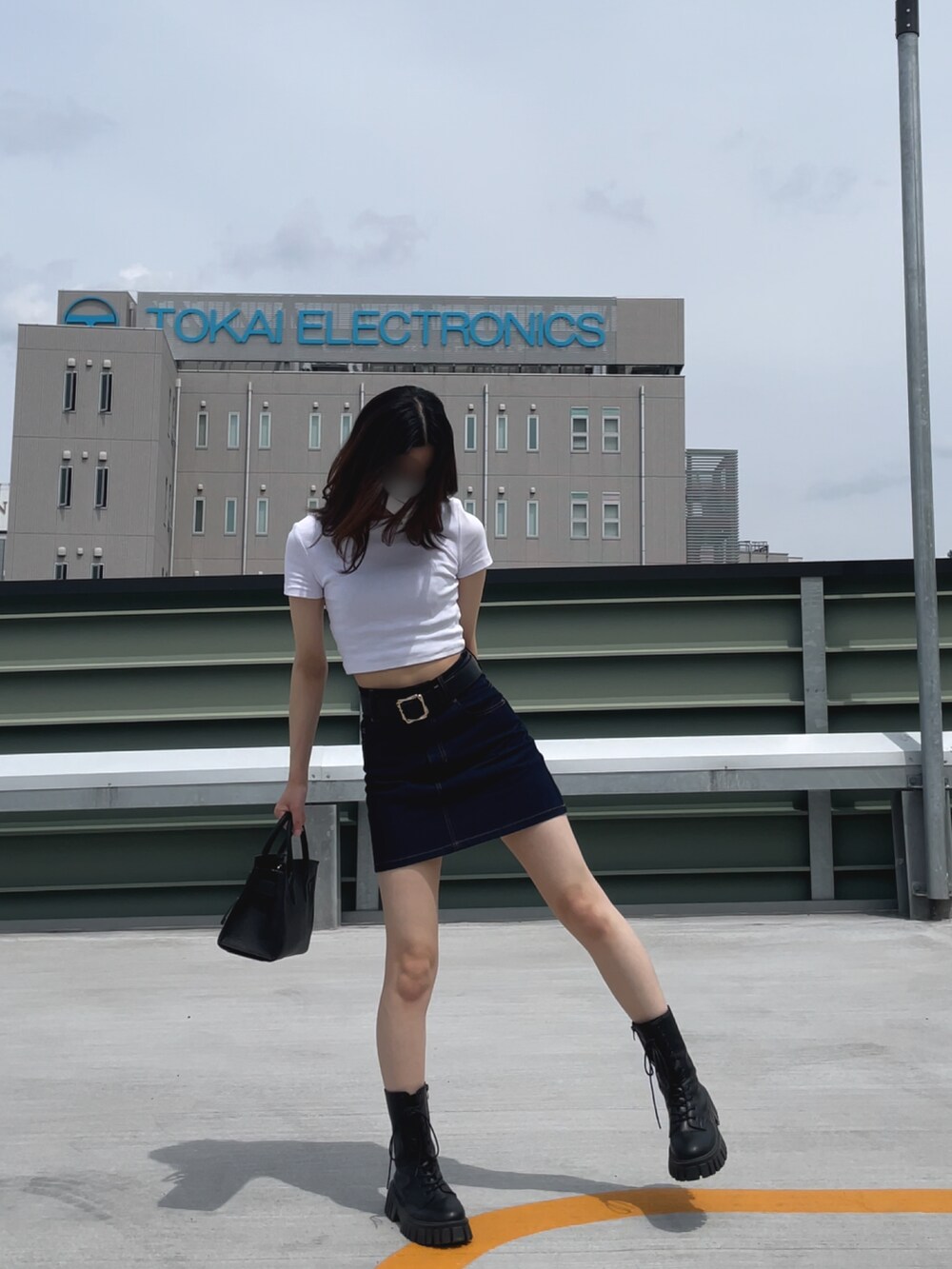 ホワイト系のトップス、ブルー系のデニムスカート、ブラック系のバッグを着用したレディースの夏コーディネートの2枚目の写真