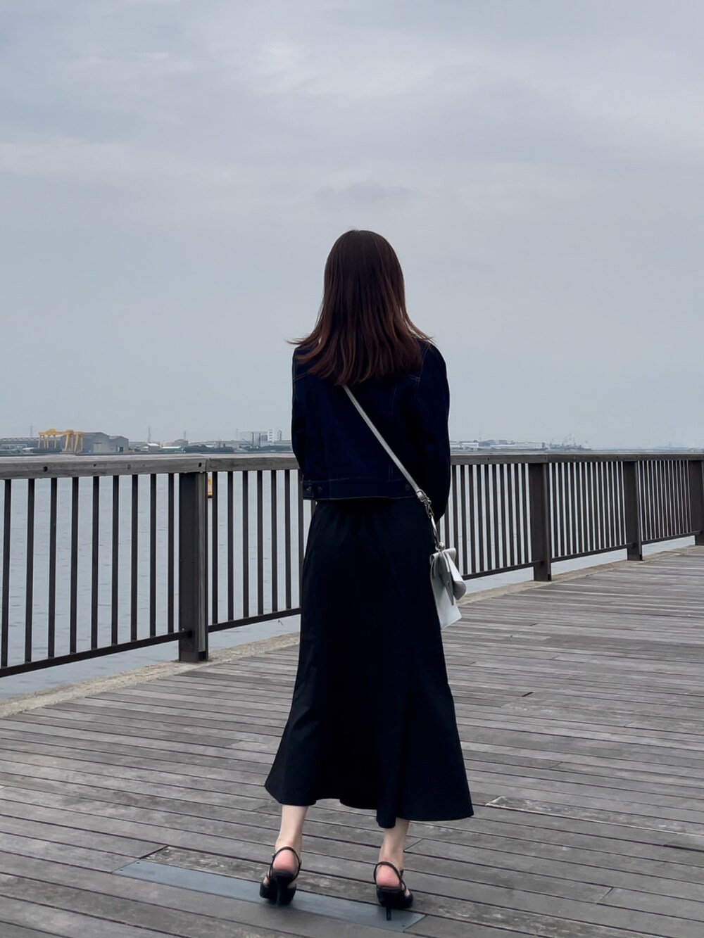 ブルー系のデニムジャケット、ホワイト系のトップス、ブラック系のスカートを着用したレディースの秋コーディネートの3枚目の写真