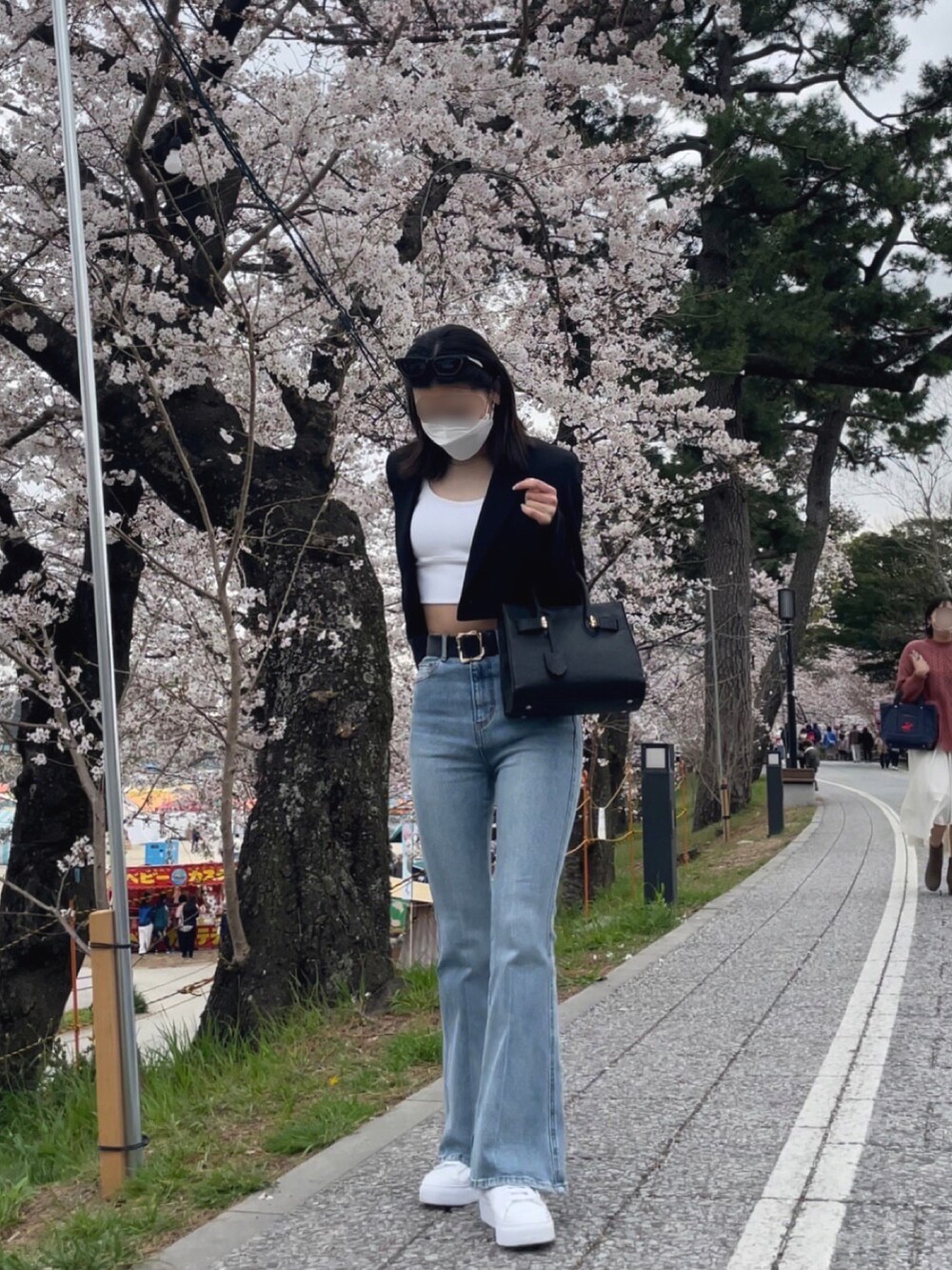 ブラック系のジャケット/アウター、ブルー系のデニムパンツ、ホワイト系のスニーカーを着用したレディースの春コーディネートの4枚目の写真