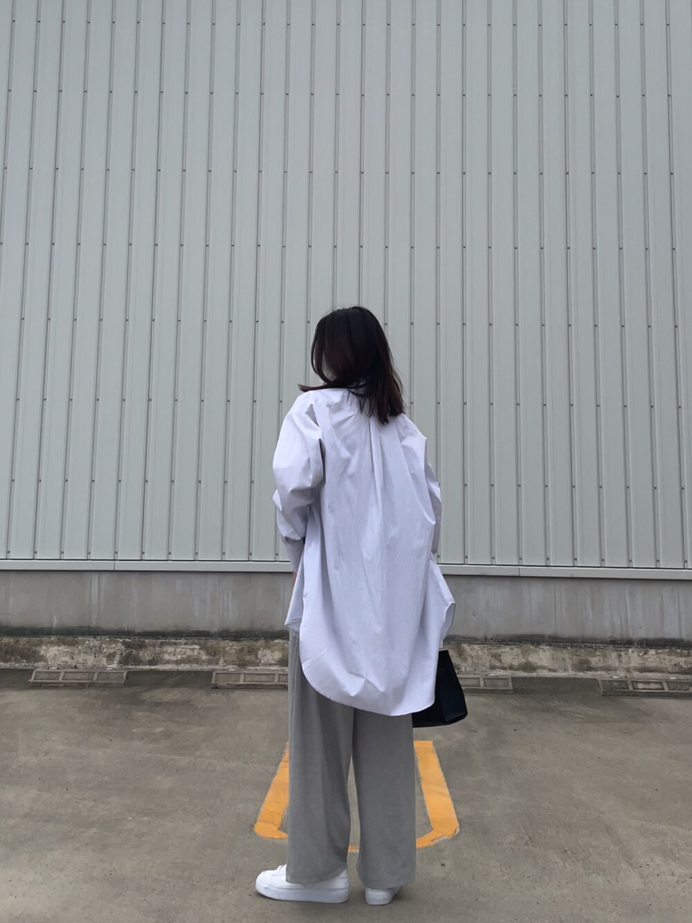 グレー系のキャミソール、ホワイト系のスニーカー、ブラック系のバッグを着用したレディースの春コーディネートの2枚目の写真