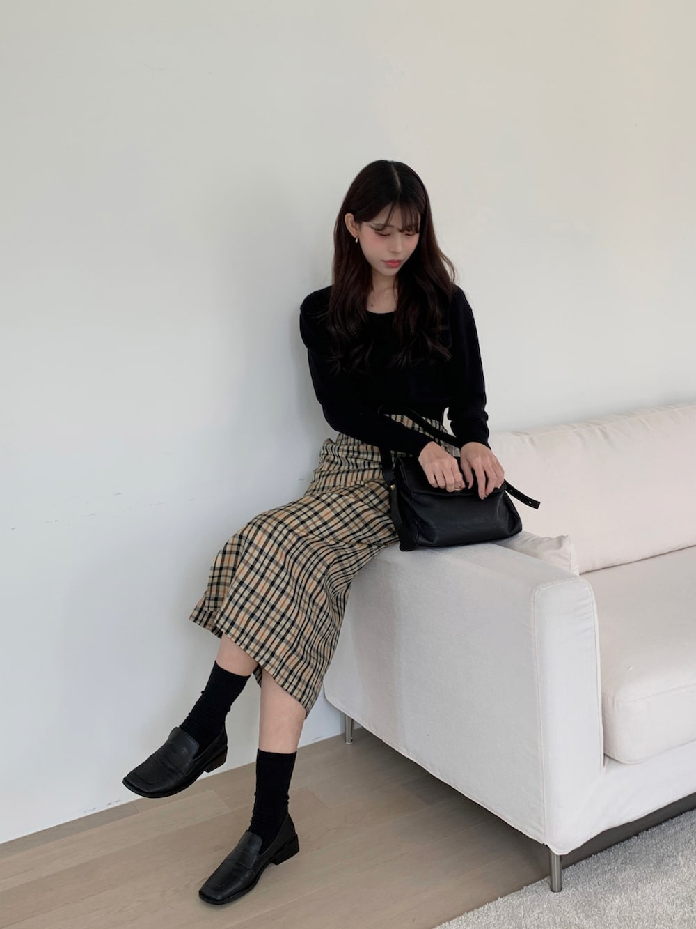 ブラック系のショルダーバッグ、ベージュ系のスカート、ブラック系のニット/セーターを着用したレディースの冬コーディネートの2枚目の写真