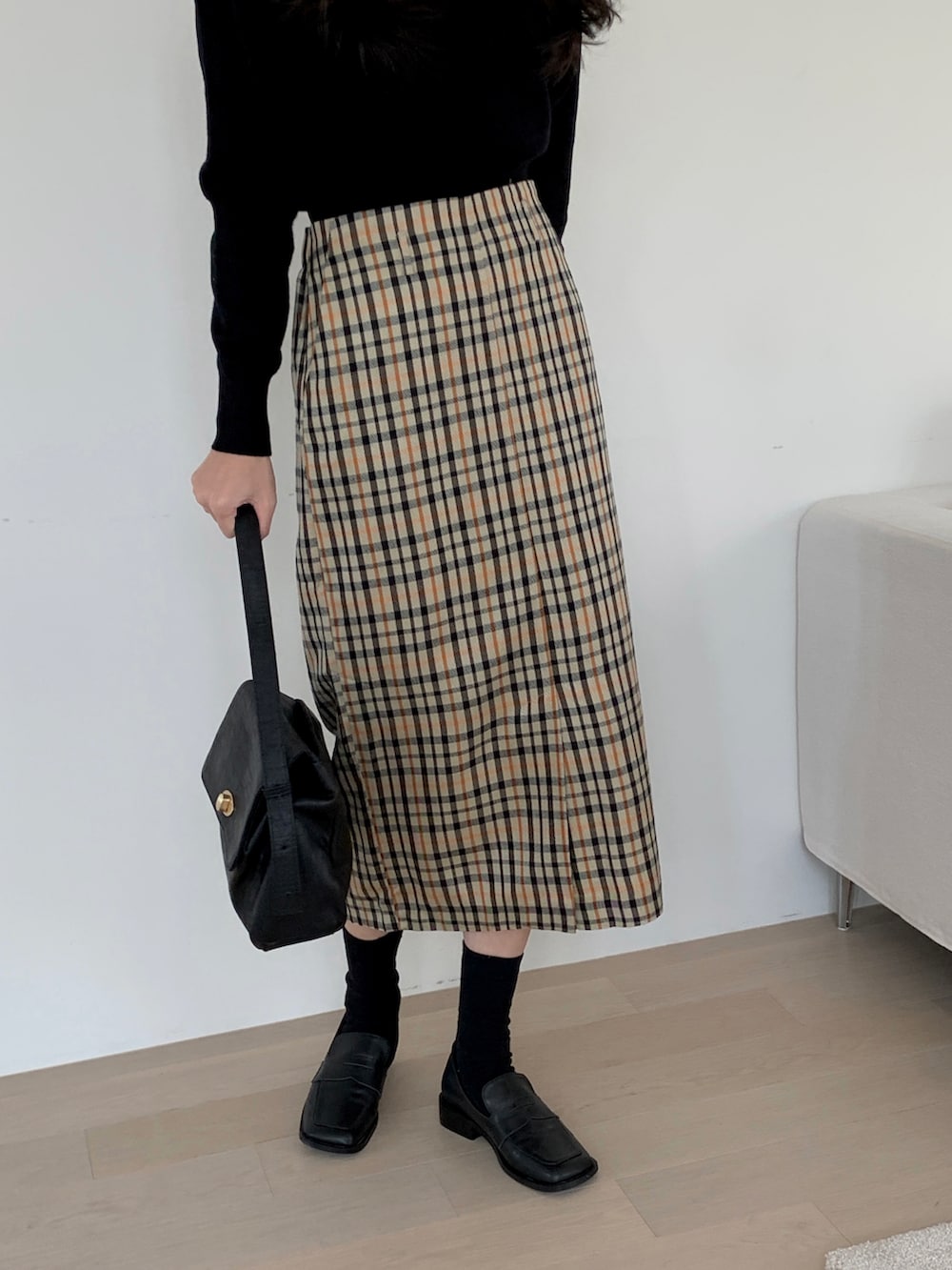 ブラック系のショルダーバッグ、ベージュ系のスカート、ブラック系のニット/セーターを着用したレディースの冬コーディネートの3枚目の写真