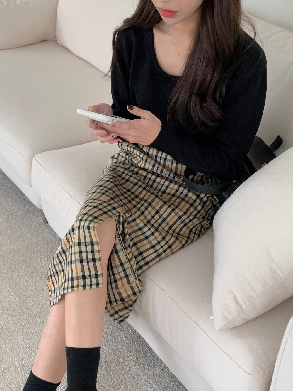 ブラック系のショルダーバッグ、ベージュ系のスカート、ブラック系のニット/セーターを着用したレディースの冬コーディネートの5枚目の写真