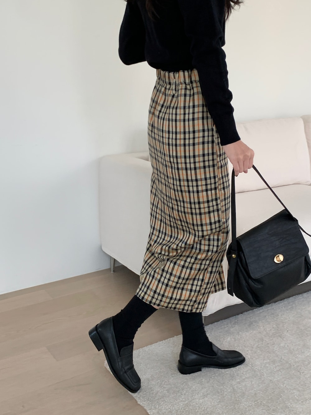 ブラック系のショルダーバッグ、ベージュ系のスカート、ブラック系のニット/セーターを着用したレディースの冬コーディネートの4枚目の写真