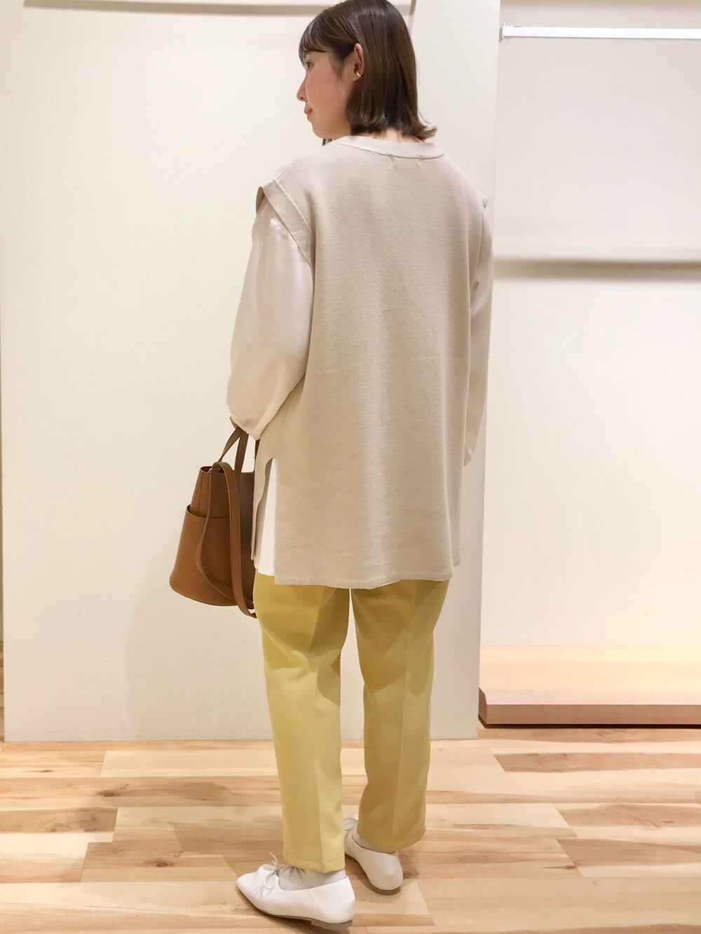 ブラウン系のトートバッグ、ベージュ系のベスト、ホワイト系のシャツ/ブラウスを着用したレディースの春コーディネートの2枚目の写真