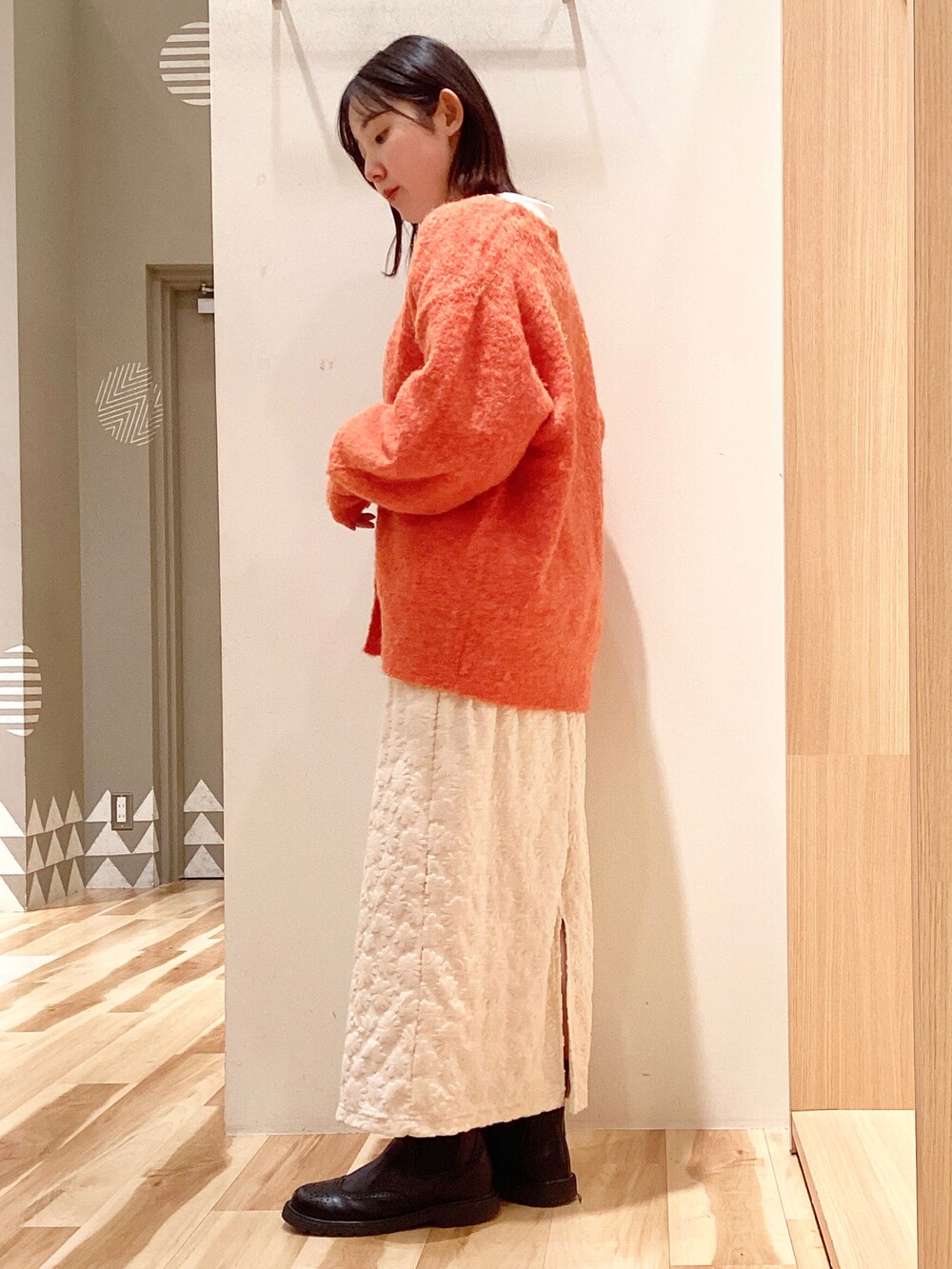 オレンジ系のカーディガン/ボレロ、ホワイト系のTシャツ/カットソー、ホワイト系のスカートを着用したレディースの冬コーディネートの2枚目の写真