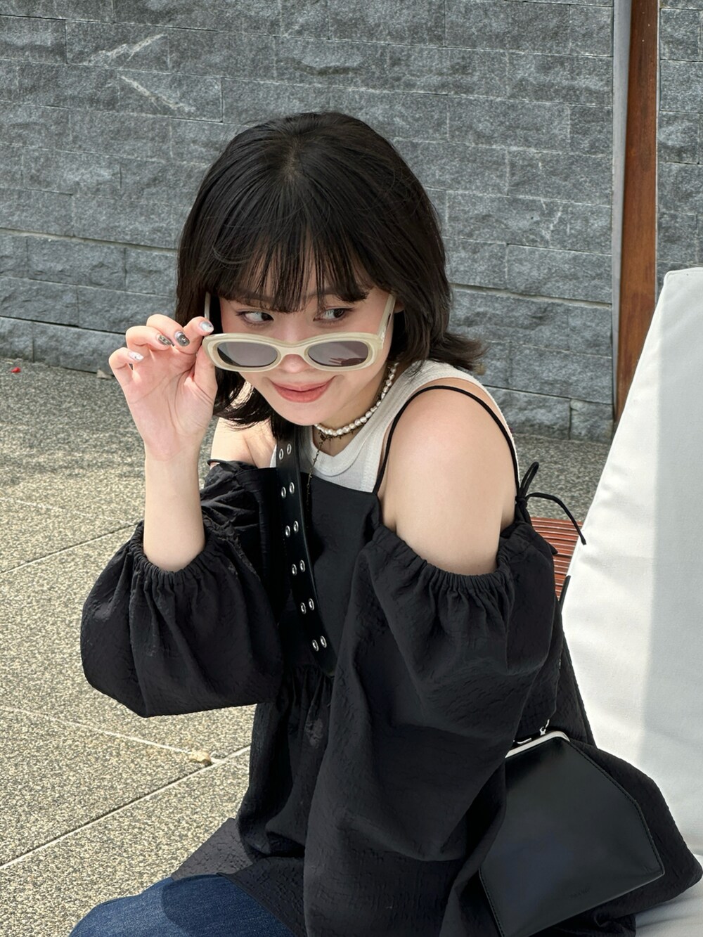 ブラック系のワンピース、ブラック系のショルダーバッグ、ブルー系のデニムパンツを着用したレディースの春コーディネートの3枚目の写真