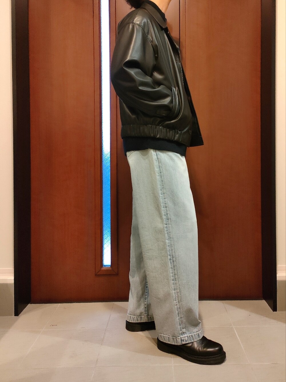 ブルー系のニット/セーター、ブラック系のブルゾン、ブルー系のデニムパンツを着用したメンズの秋コーディネートの2枚目の写真