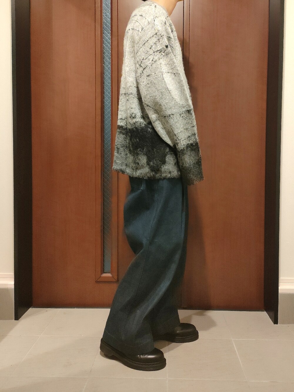 グレー系のニット/セーター、ブルー系のデニムパンツ、ブラック系のブーツを着用したメンズの秋コーディネートの2枚目の写真